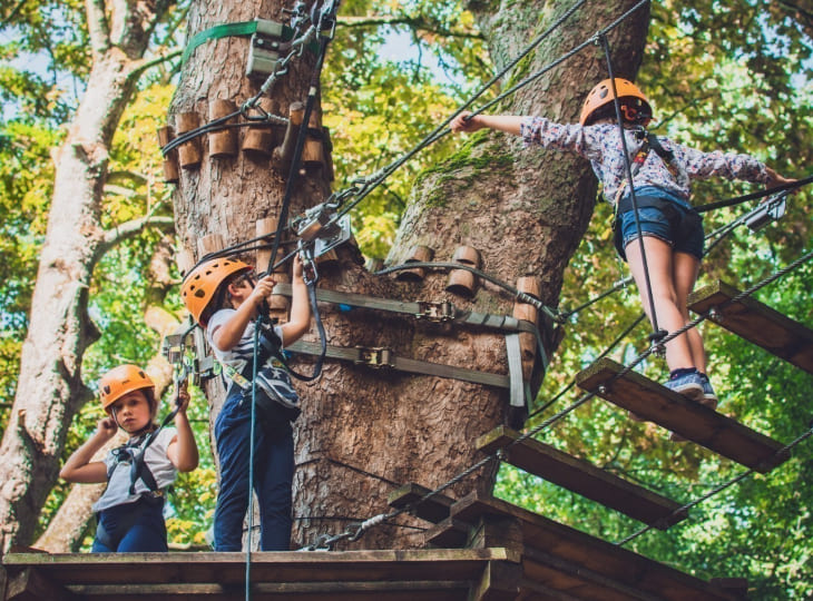 Enfants avec casques et harnais sur un parcours d'accrobranche à Accro Lille au Parc de la Citadelle.