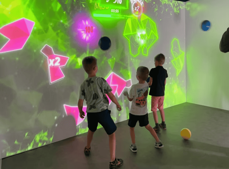 Groupe d'enfants jouant à un jeu de ballon interactif sur mur numérique chez Koezio, idée de sortie anniversaire à Lille.