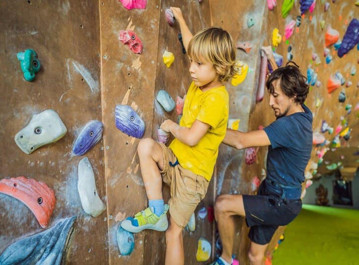 Enfant pratiquant l'escalade sur un mur coloré à l'Île Tortuga, parc de jeux couvert pour enfants près de Lille.