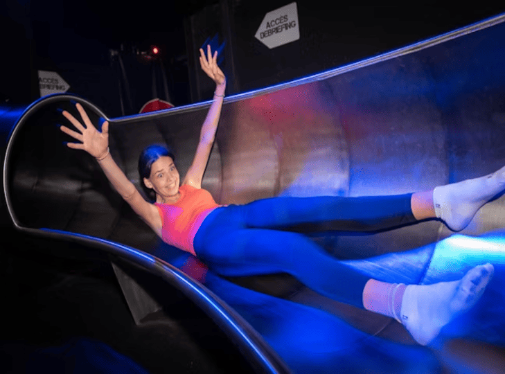 eune femme descendant un grand toboggan intérieur chez Koezio Lille, parc d'aventure et de loisirs actif.