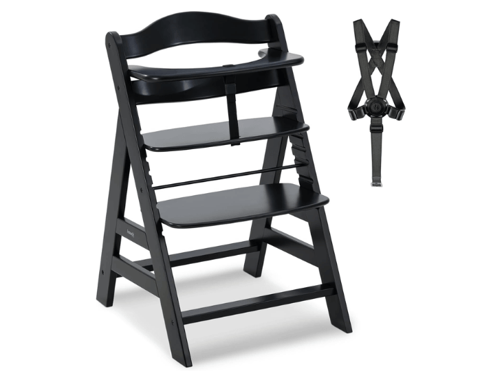 Chaise haute en bois Hauck Alpha + noire, présentée avec son harnais de sécurité à 5 points à côté.
